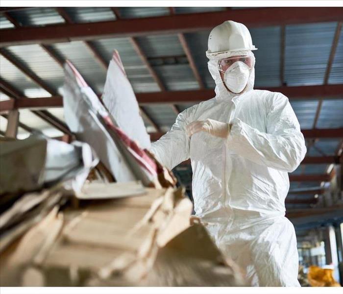 worker wearing biohazard suit sorting reusable cardboard